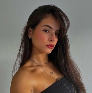 Mulher branca, cabelos feitos com prancha sorrindo com camiseta de gola alta preta.