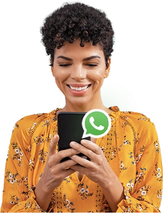 Mulher negra com cabelos encaracolados, segurando e olhando para o celular que está em suas mãos e um ícone do WhatsApp sobre o celular.